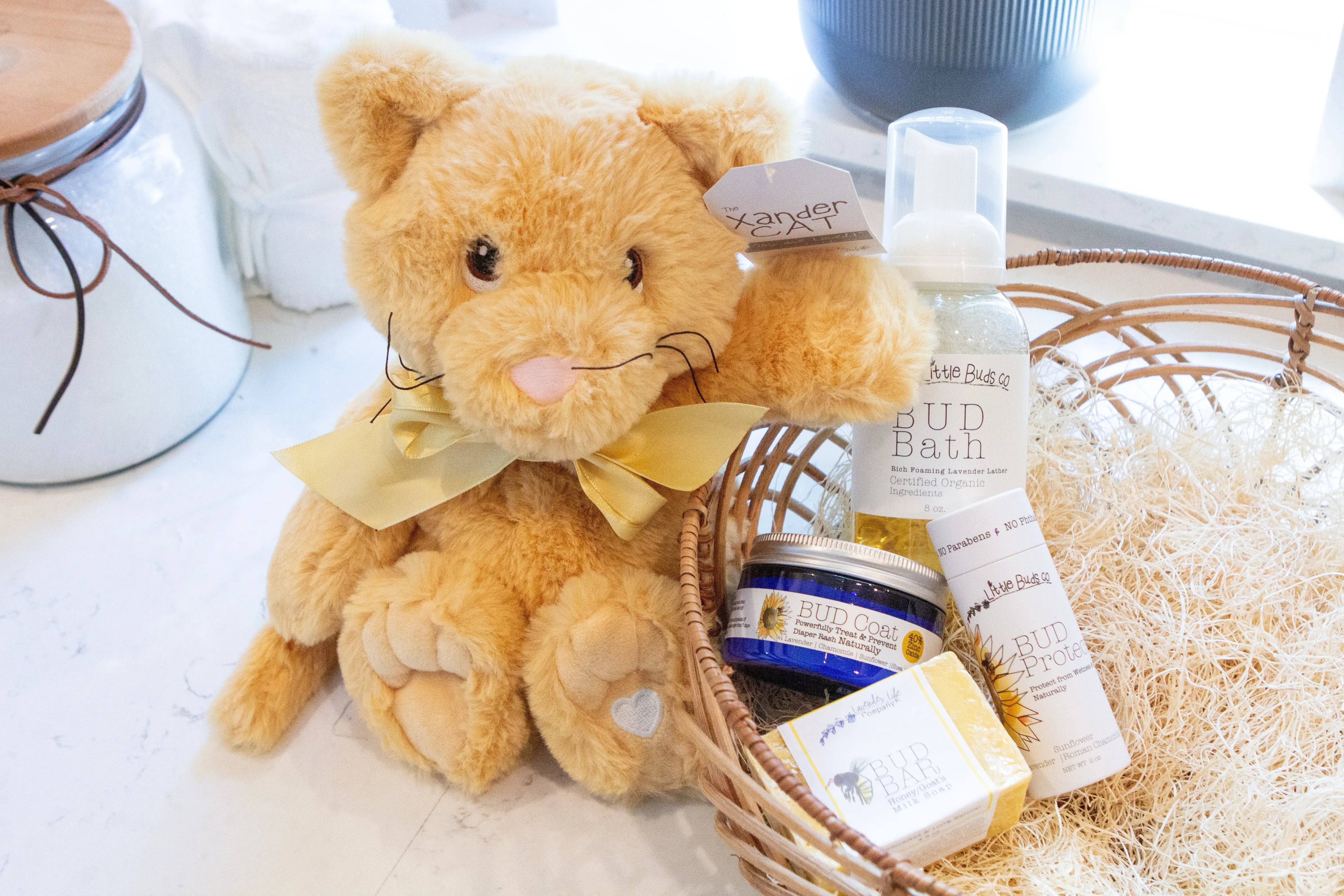 xander cat sitting next to a basket full of lavender life baby products for skin and bath