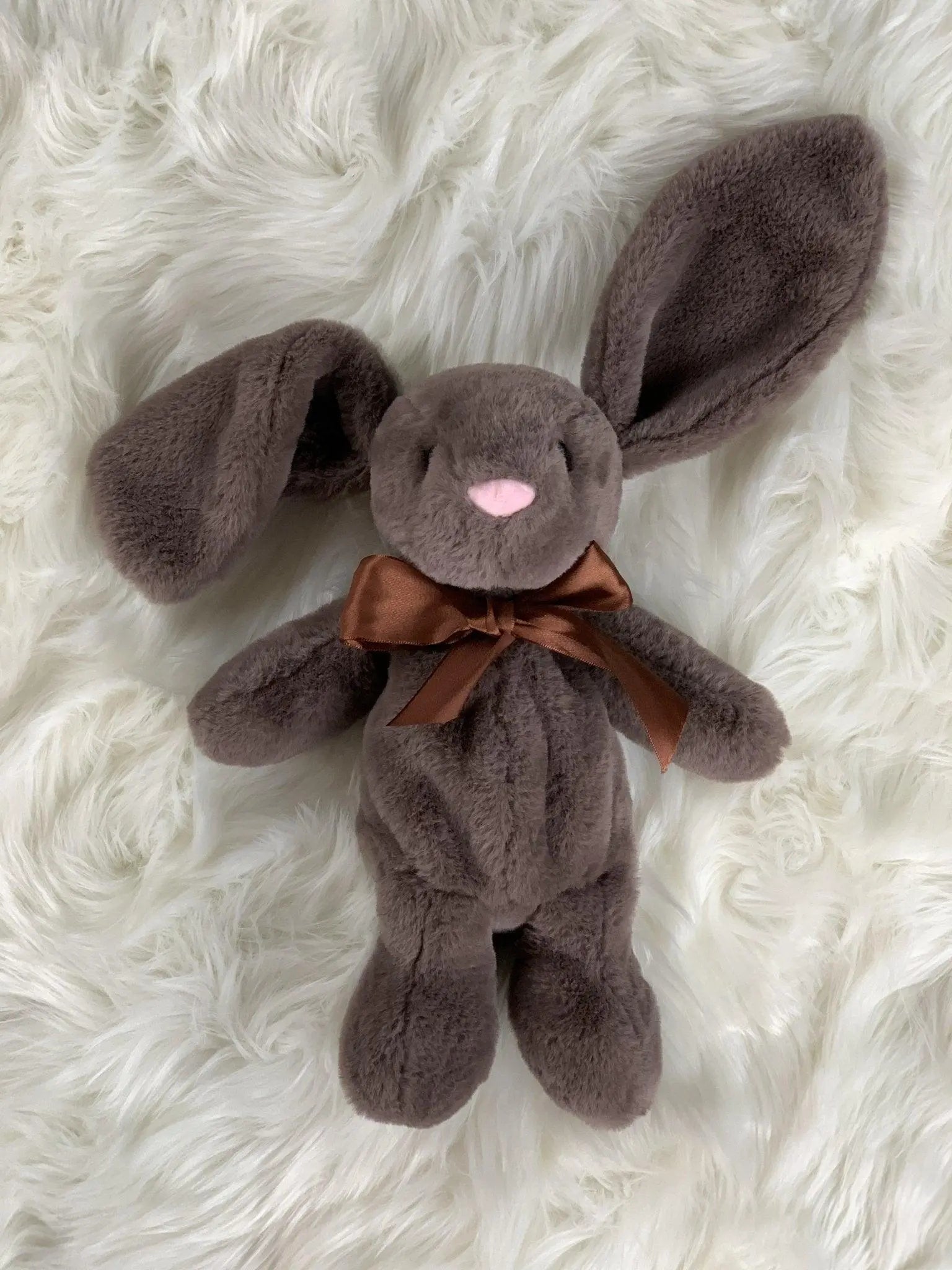 Xander bunny in mocha laying on a white hair rug