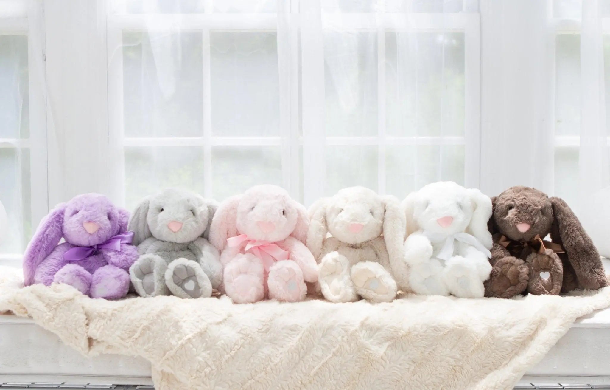 xander friends bunnies sitting on a shelf in front of a window in varying colors of purple to mocha