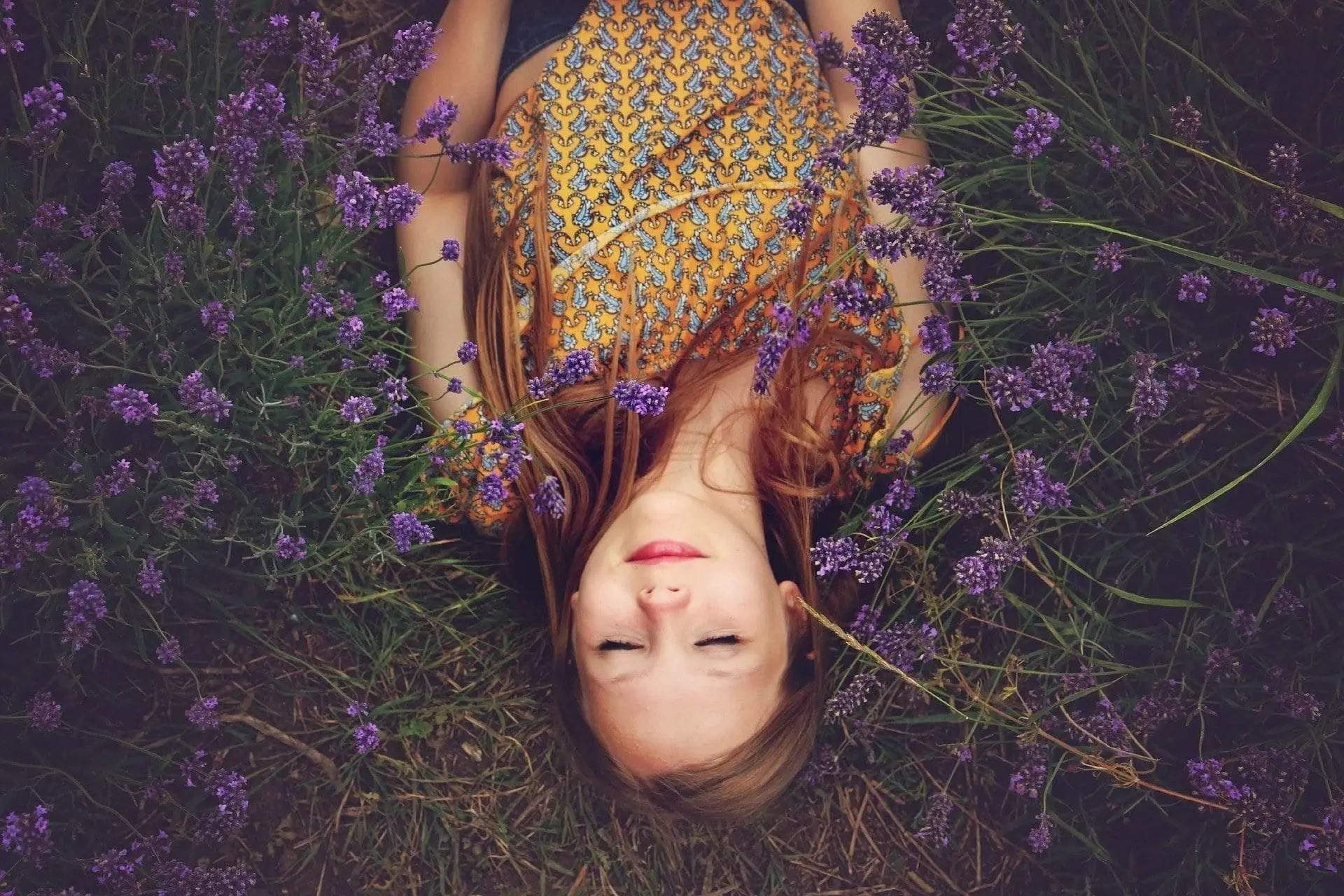 woman laying asleep in a garden of lavender flowers