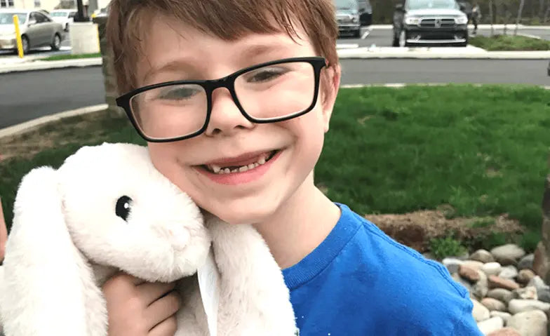 Little boy with glasses holding a White Xander Bunny