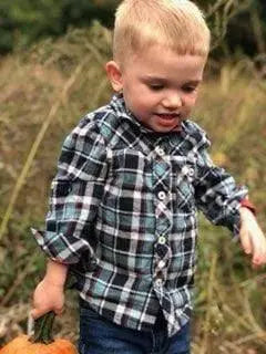 Little blonde haired boy about 2 walking through a pumpkin patch