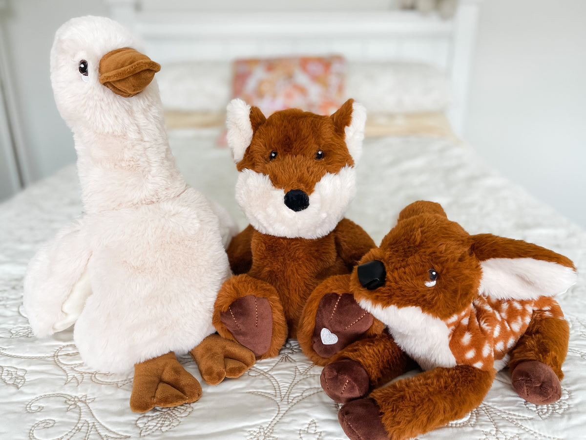 Xander Duck, Fox and Fawn lavender plush together on a cream quilt