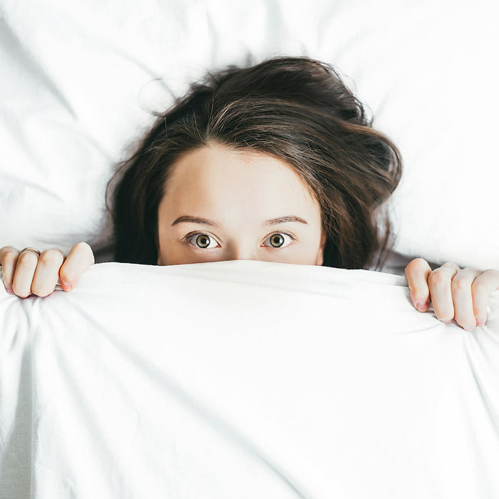 A woman lying awake in bed with the covers pulled up
