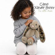Child holding a plush bunny toy with camouflage ears, branded 'Camo Xander Bunny for Little Heroes'.